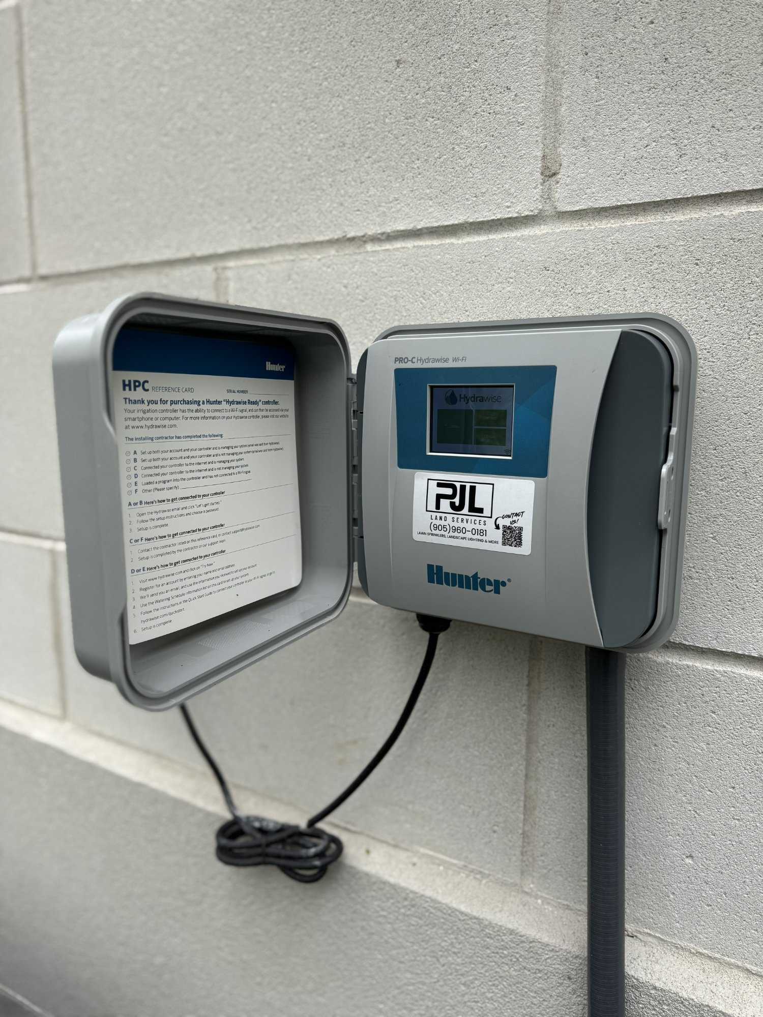 Hunter HPC-400 Hydrawise Pro-C Wi-Fi controller mounted on a wall with a PJL Land Services sticker