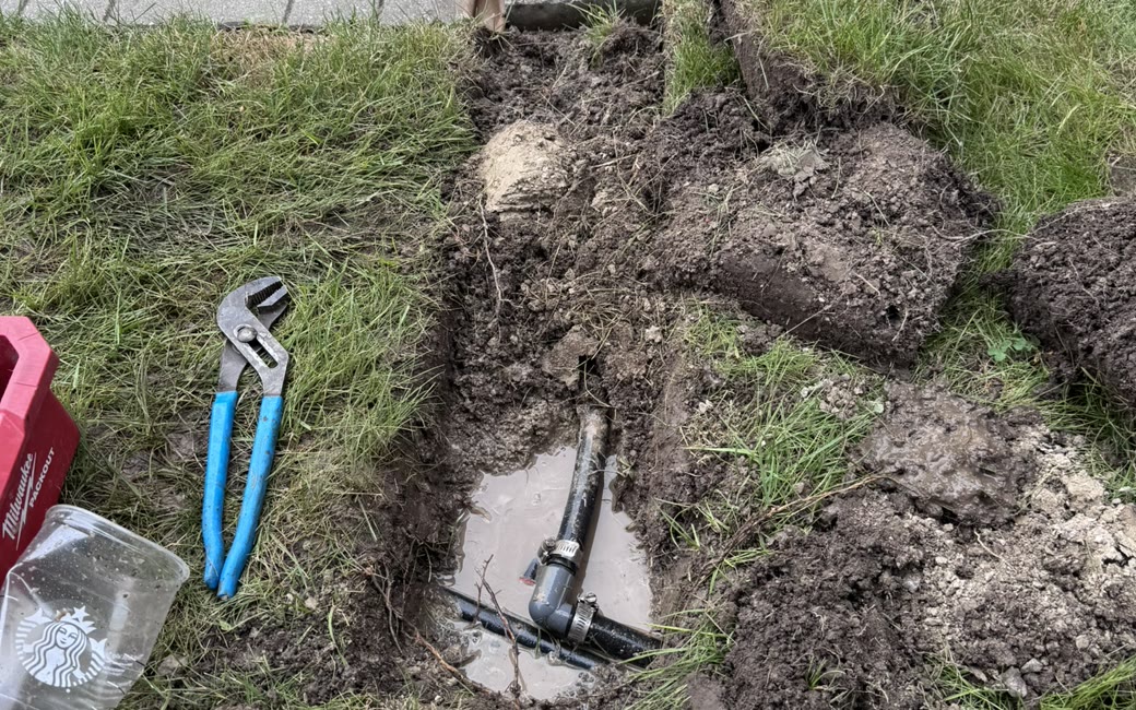 A PJL excavation exposing a broken sprinkler pipe and fitting next to channel-lock pliers
