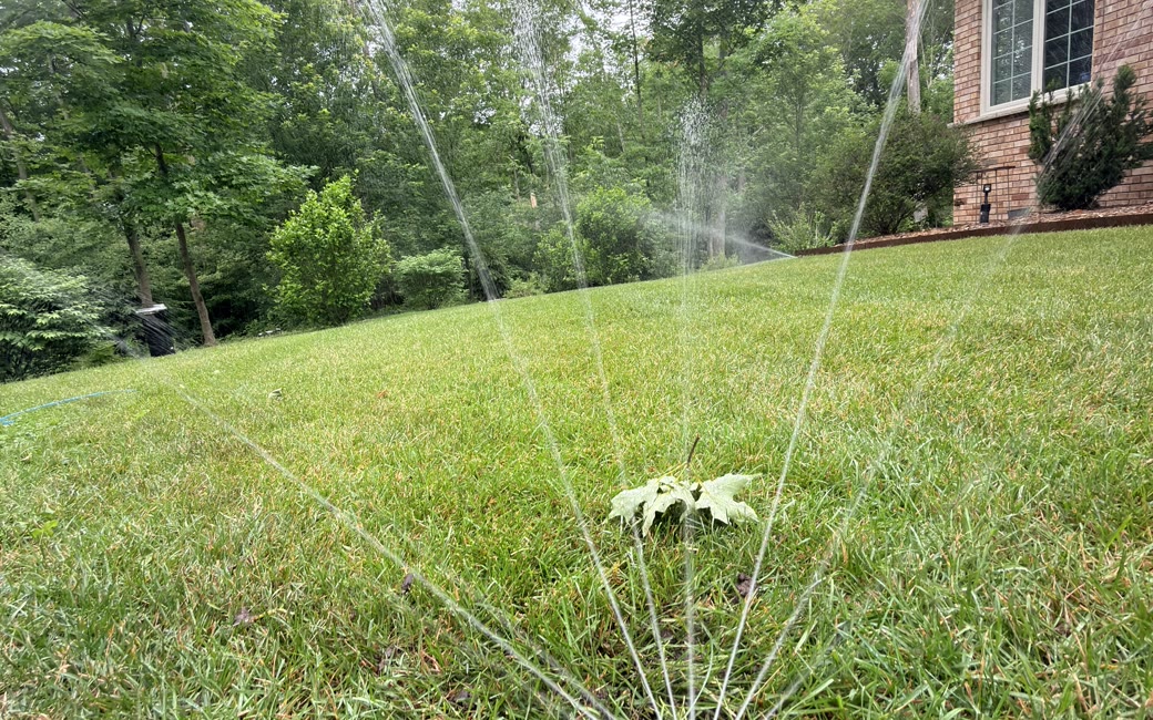 A rotor sprinkler throwing multiple streams across a lawn to fix dry spots