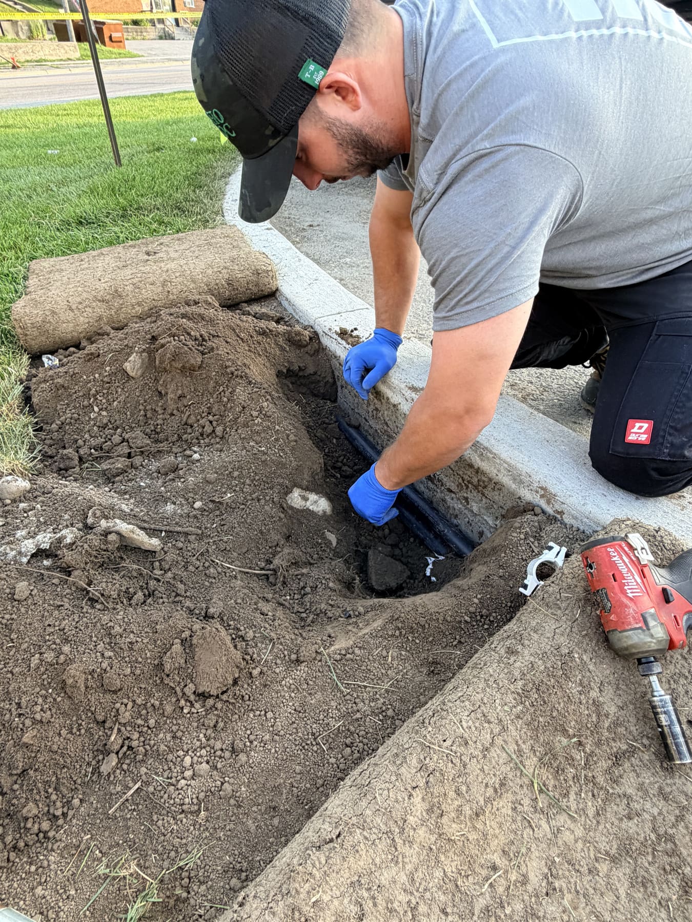 A PJL Land Services technician working an irrigation mainline repair in an open sod trench in Newmarket