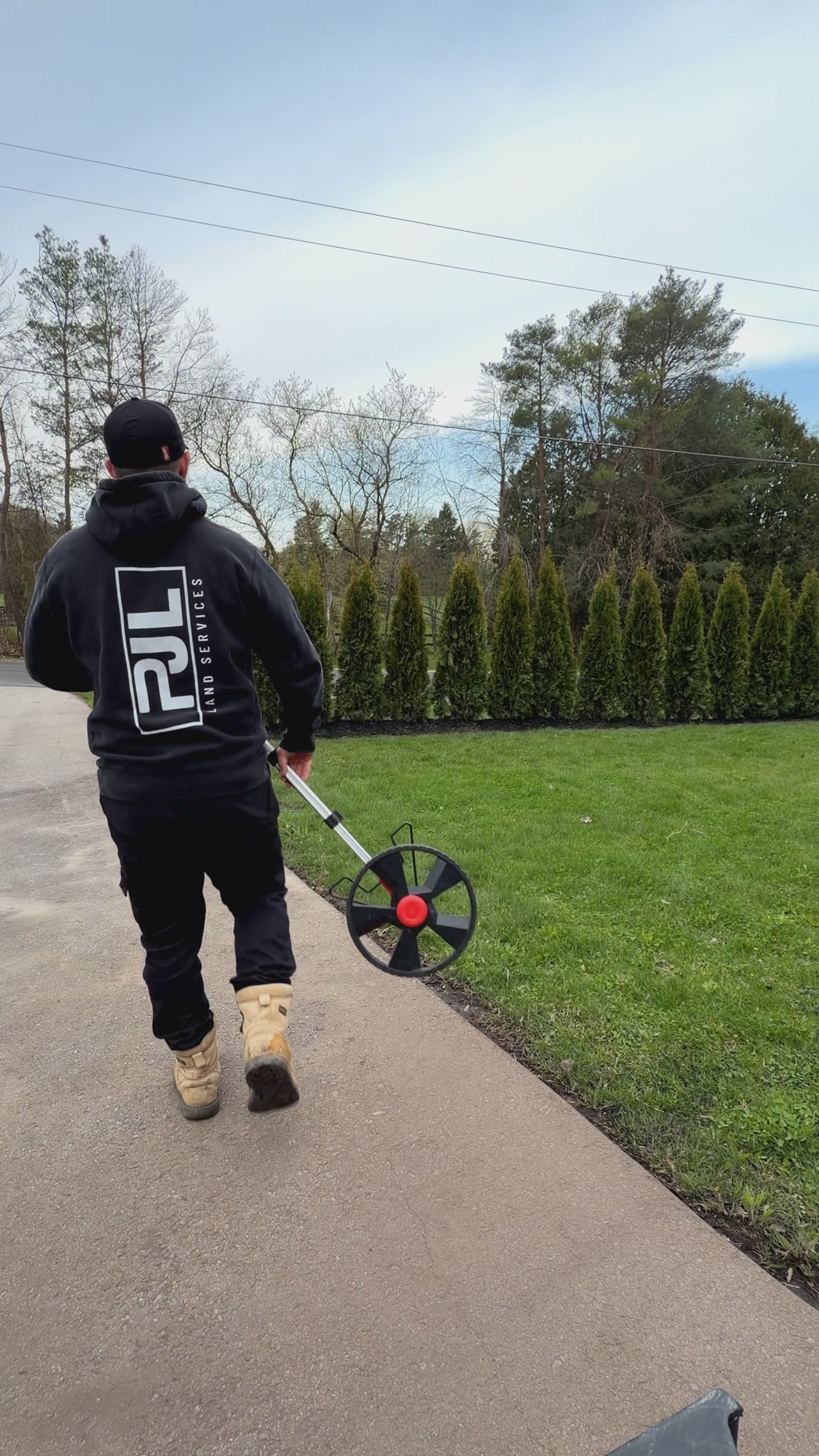 PJL Land Services technician using a measuring wheel to survey a residential property in York Region before a sprinkler system design.